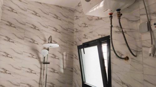 eine Dusche in einem Badezimmer mit einer weißen Marmorwand in der Unterkunft CAMMS 2 Studios in Rufisque