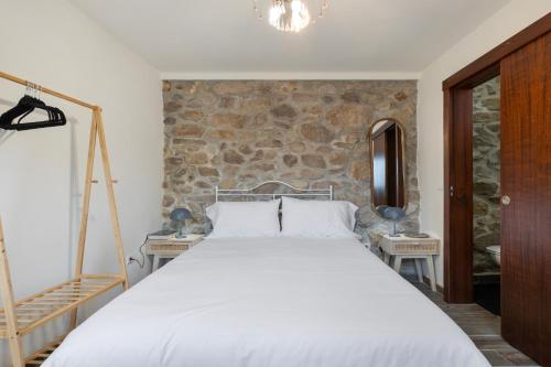 a bedroom with a white bed and a stone wall at Casa do Monte - Monção in Poças do Monte