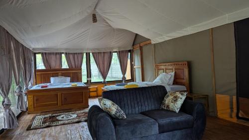 a bedroom with a couch and a bed in a tent at Tctc & Camp in Shikurufumi