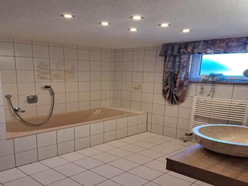 a bathroom with a tub and a sink and a window at Ferienwohnung Waldoase 