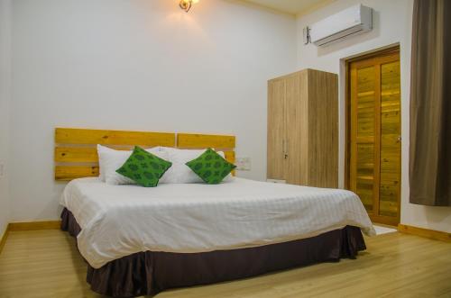 a bedroom with a large white bed with green pillows at Holiday Garden Rasdhoo in Rasdu
