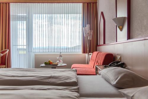 a hotel room with a bed and a chair at Hessen Hotelpark Hohenroda in Hohenroda