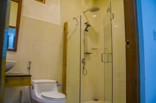 a bathroom with a toilet and a glass shower at Holiday Garden Rasdhoo in Rasdu
