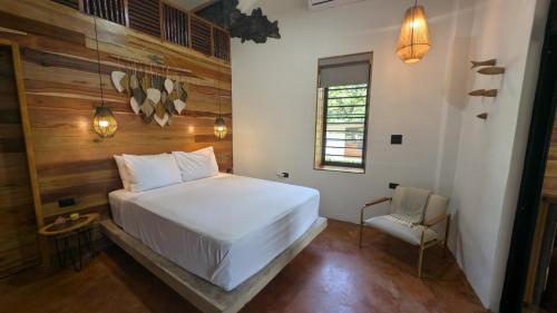 a bedroom with a white bed and a chair at Beyond Alma Del Rio in Cristo Rey