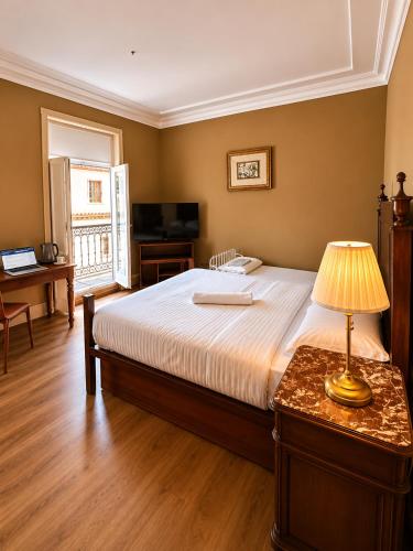 a bedroom with a bed and a table with a lamp at Casa Quixote, Centro Catedral in Braga