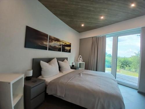 a bedroom with a bed and a large window at Bungalow Vulkanblick in Manderscheid