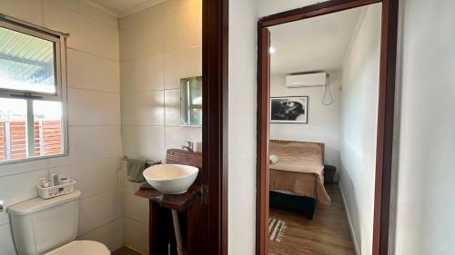 a bathroom with a sink and a toilet and a bed at Aurora in Carmelo