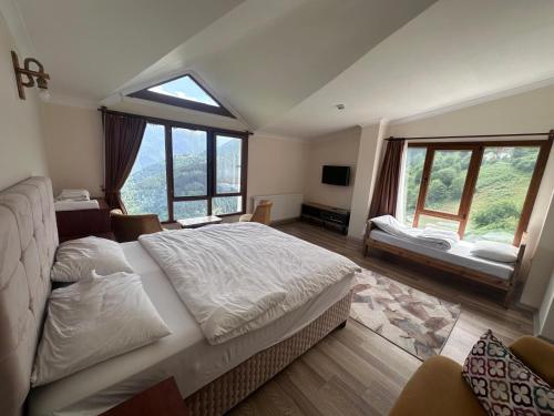 a bedroom with a large bed and large windows at Meşeiçi Butik Aile Otel in Macka