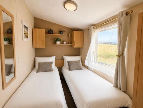 two beds in a small room with a window at Seaside Escape at St Osyth in Clacton-on-Sea