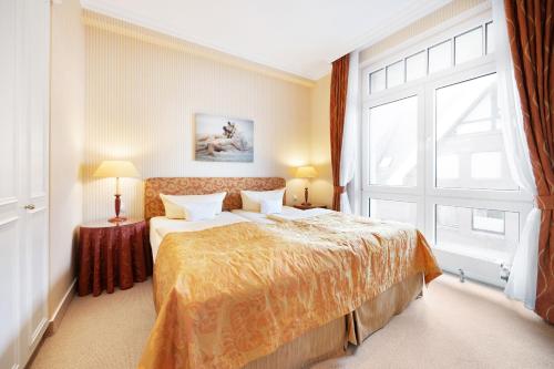a bedroom with a bed and a large window at Strandhotel Sylt Westerland in Westerland