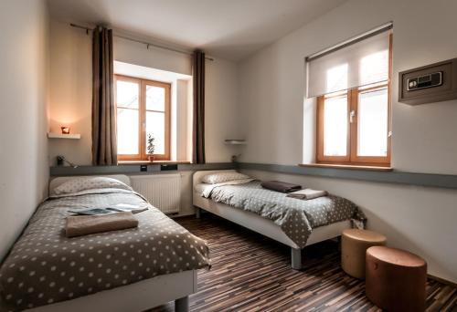 two beds in a room with two windows at CUBE central rooms for 2 in Ljubljana