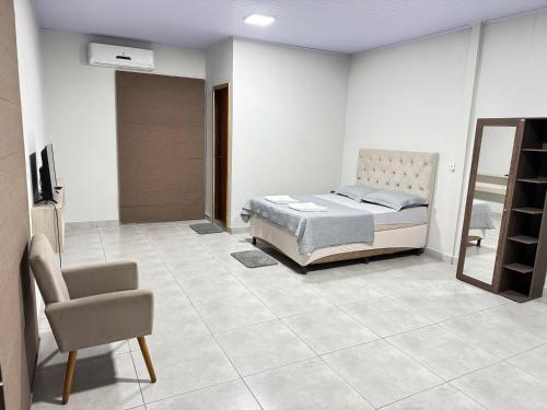 a bedroom with a bed and a chair at Apartamento privado in Primavera do Leste