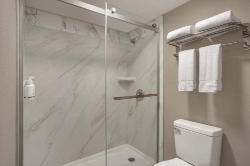 a white bathroom with a shower and a toilet at Ramada by Wyndham Cocoa in Cocoa