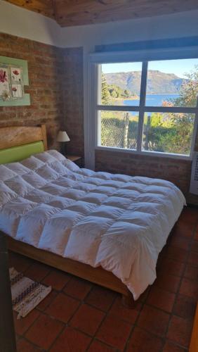 a large bed in a bedroom with a large window at Cabañas Mateo in Villa Pehuenia