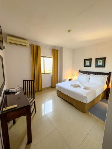 a hotel room with a bed and a table and a desk at Vip Executive Suites Maputo in Maputo