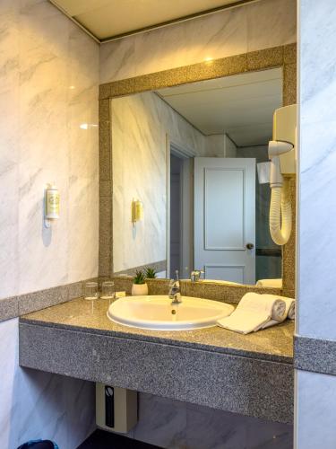 a bathroom with a sink and a large mirror at Vip Executive Suites Maputo in Maputo