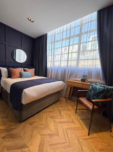 a bedroom with a bed and a desk and a window at Hütel in Liverpool