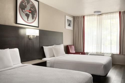 a hotel room with two beds and a window at Ramada by Wyndham Cocoa in Cocoa