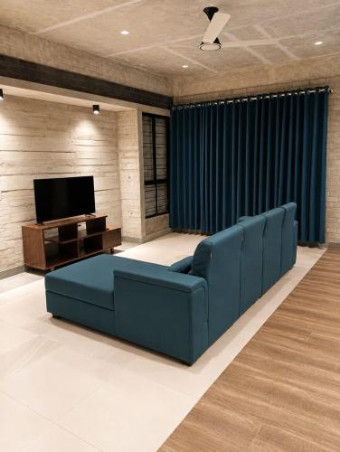 a living room with a blue couch and a television at HomeWay Dhaka in Kāmarpāra