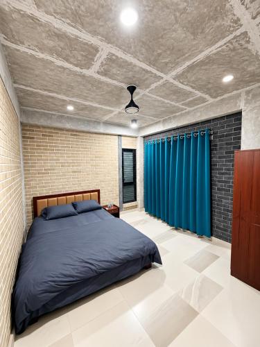 a bedroom with a bed and a blue curtain at HomeWay Dhaka in Kāmarpāra