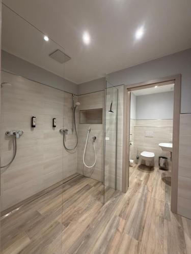 a bathroom with a glass shower and a toilet at Hotel Ostseewoge in Graal-Müritz
