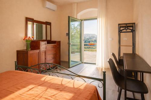 a bedroom with a bed and a desk and a window at Eterea Dimora Sul Fiume in Noto