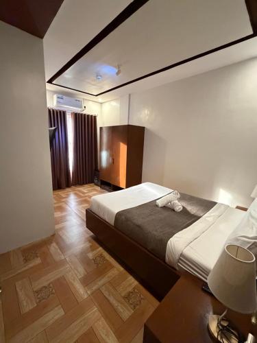 a hotel room with a bed and a table with a lamp at JJPHR Hotel San Antonio in Lubao