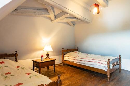 a bedroom with two beds and a table with a lamp at Vue magique Coeur de Beynac in Beynac-et-Cazenac