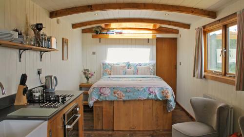 a small kitchen with a bed in a tiny house at Betty Shepherd's Hut in Lydney
