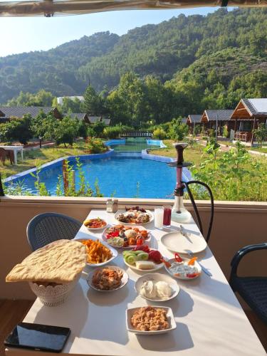 a table with food on it with a view of a pool at Ruby Bungalow Alanya in Yaylalı
