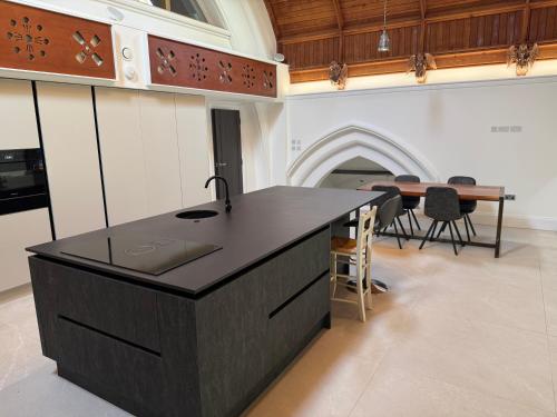 a kitchen with a black island in a room with a table at The North Wing in Stotfold