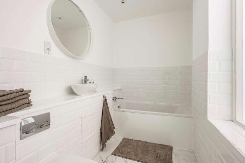 a white bathroom with a sink and a tub at Seven Space - The Old Post Office Court in Norwich