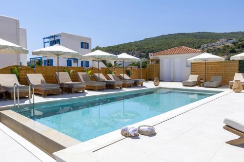 a swimming pool with lounge chairs and umbrellas at Laza Beach in Skala