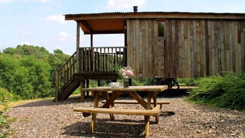 a picnic table in front of a wooden cabin at Bertha Shepherd's Hut in Lydney