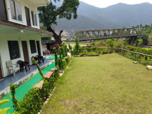 a house with a yard with a bridge in the background at Uttarkashi Resort in Uttarkāshi