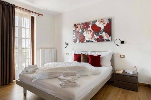 a white bedroom with a large bed with red pillows at Katy Lake Timo in Sirmione