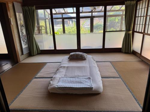 a bed in the middle of a room with windows at Kouan 功庵 in Matsuyama