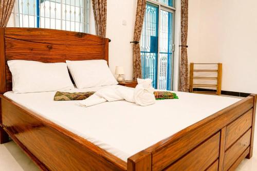 a bedroom with a large wooden bed with white sheets at Uroa Beachfront Apt Direct Sand in Uroa