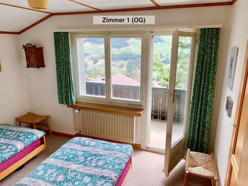 a bedroom with two beds and a large window at Chalet Panorama in Adelboden