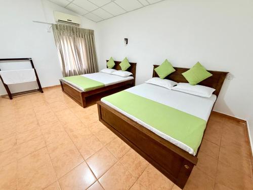 a bedroom with two beds with green and white sheets at Villa 87 - Anuradhapura in Anuradhapura