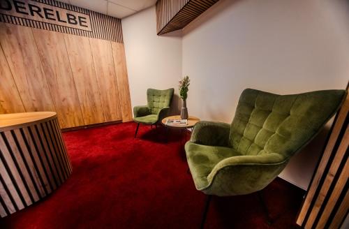 ein Zimmer mit zwei grünen Stühlen und einem roten Teppich in der Unterkunft Hotel Süderelbe in Hamburg