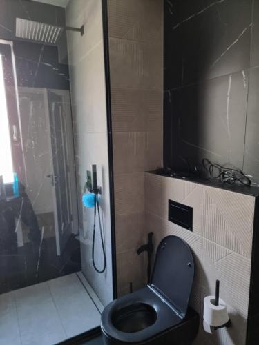 a bathroom with a black toilet and a shower at Donath park view in Baciu