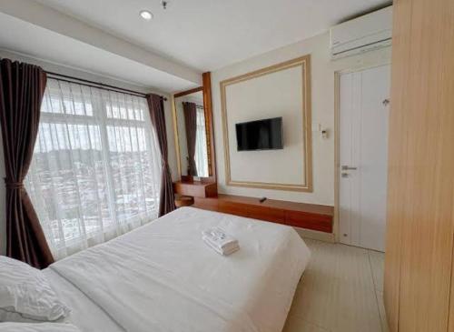 a bedroom with a white bed and a large window at Pentapolis Apartment Balikpapan Superblock LT4 in Balikpapan