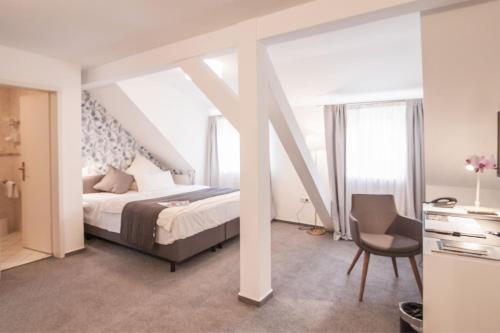 a bedroom with a bed and a desk and a chair at Hofgut Dippelshof Hotel- und Restaurant KG in Darmstadt