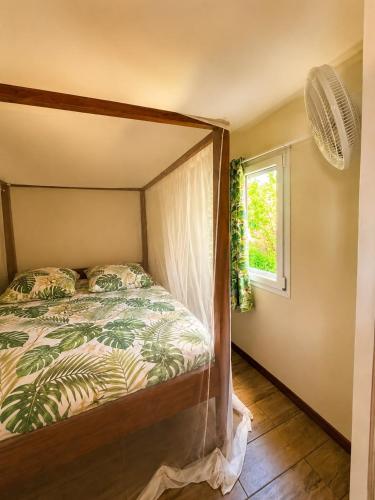 a bedroom with a canopy bed with a window at Gîte Bananier - Villa Marina in Bouillante