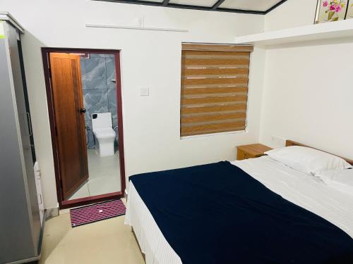 a bedroom with a bed and a bathroom with a toilet at CHRIS COZY FARM cottage in Wayanad