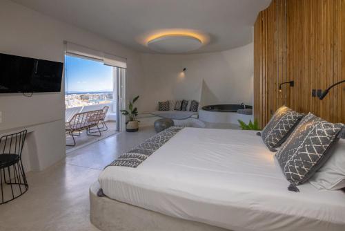 a bedroom with a large bed and a balcony at Onar Hotel & Suites in Tinos