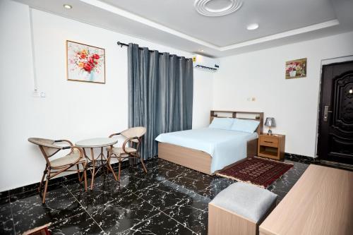 ein Schlafzimmer mit einem Bett, einem Tisch und Stühlen in der Unterkunft Motion apt in Accra