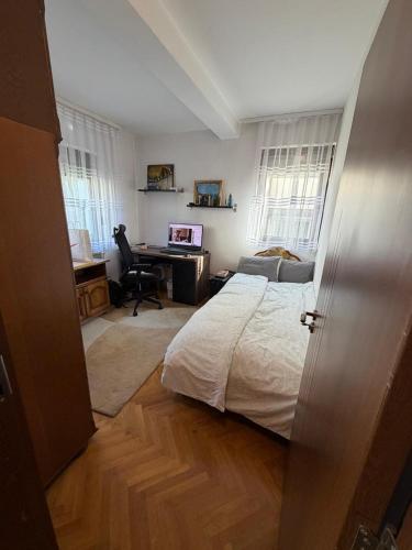 a bedroom with a bed and a desk with a computer at Safely located apartment in Prishtinë