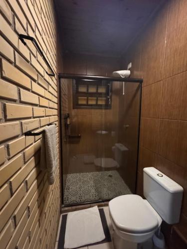 a bathroom with a toilet and a glass shower at Pousada Villa Verde - Frente para a Praia do Farol in Ilha do Mel